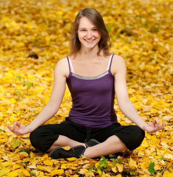 Woman doing yoga exercises in the autumn park — Stock Photo, Image