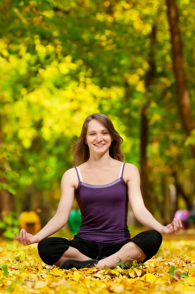 Woman doing yoga exercises in the autumn park — Stock Photo, Image