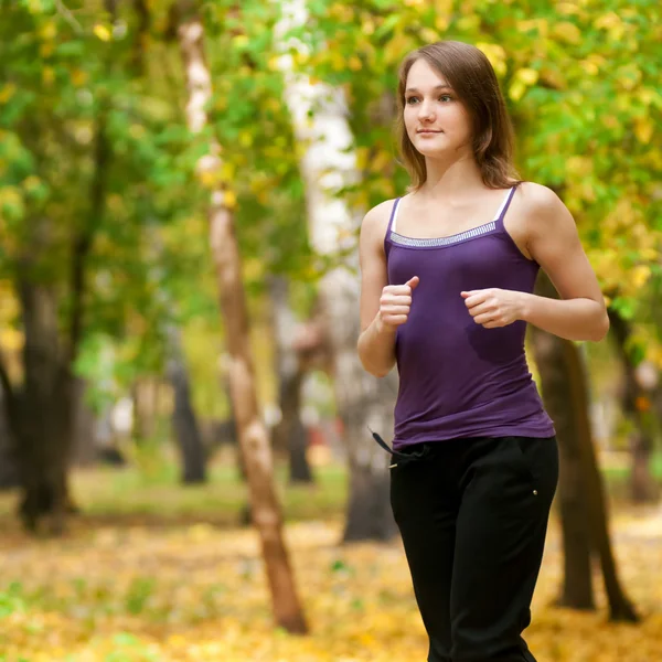 Una giovane ragazza che corre nel parco autunnale — Foto Stock