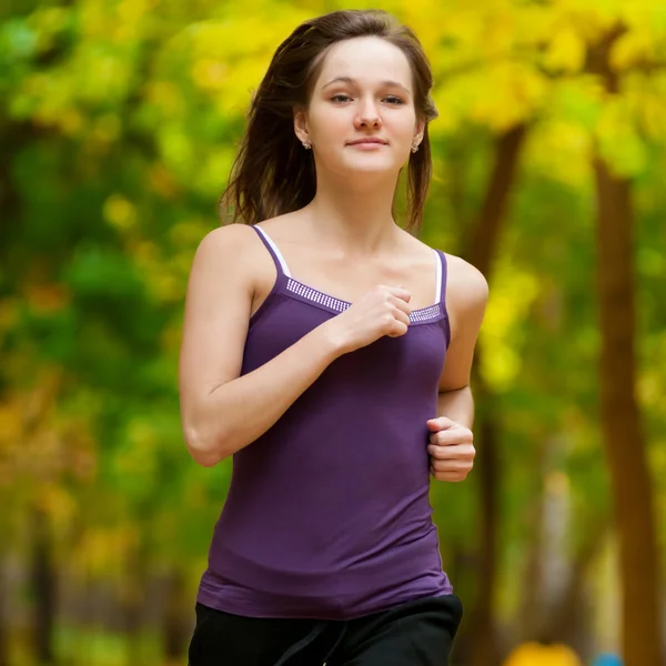 Una giovane ragazza che corre nel parco autunnale — Foto Stock