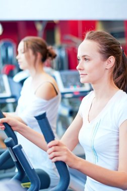 makine üzerinde çalışan iki genç sportif kadın
