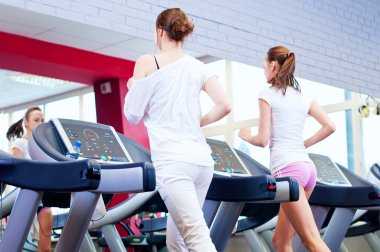 makine üzerinde çalışan iki genç sportif kadın