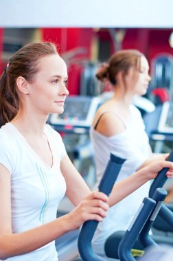 makine üzerinde çalışan iki genç sportif kadın