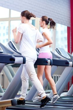 makine üzerinde çalışan iki genç sportif kadın