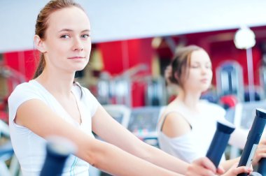 makine üzerinde çalışan iki genç sportif kadın