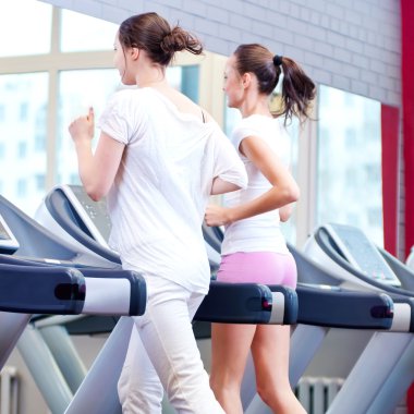 makine üzerinde çalışan iki genç sportif kadın