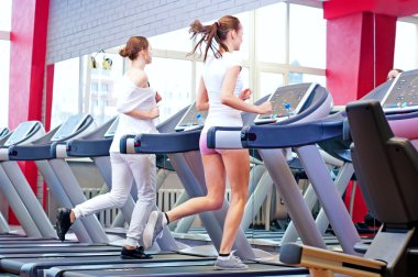makine üzerinde çalışan iki genç sportif kadın