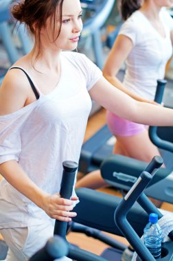 makine üzerinde çalışan iki genç sportif kadın