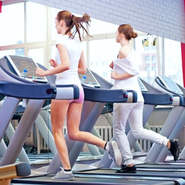 makine üzerinde çalışan iki genç sportif kadın