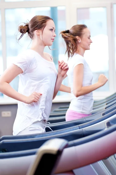 Two young sporty women run on machine — Stock Photo, Image