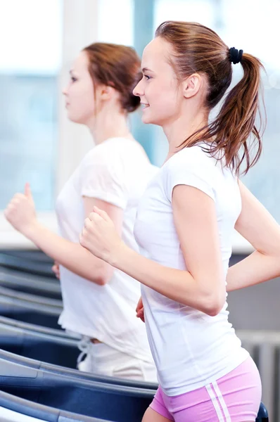 Two young sporty women run on machine — Stock Photo, Image