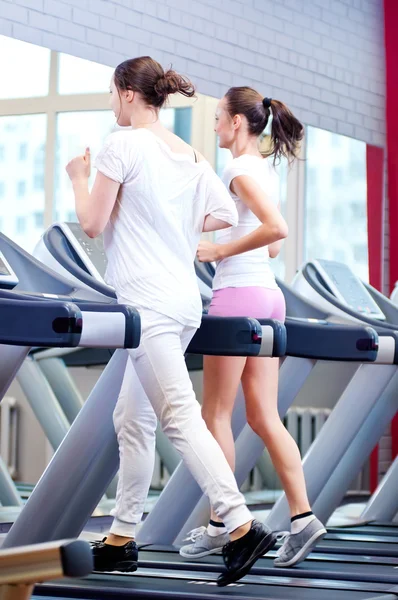 Two young sporty women run on machine — Stock Photo, Image