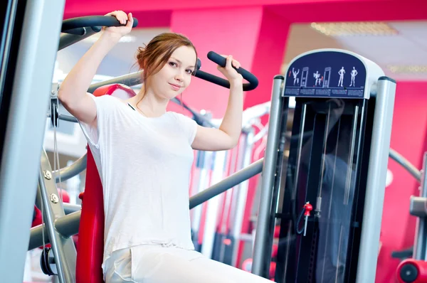 Woman doing splits on machine with weights — Stock Photo, Image