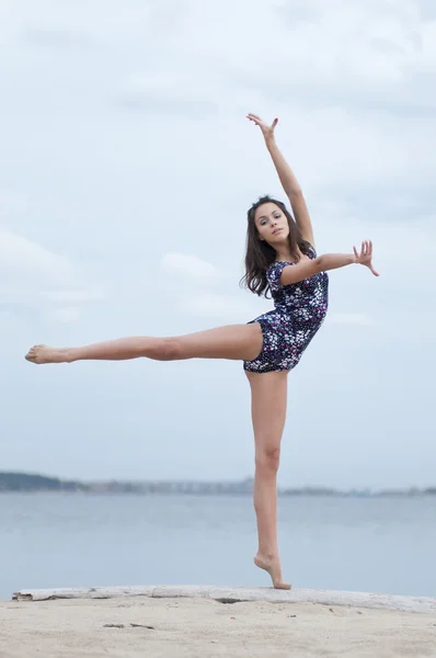 Молодая гимнастка танцует на пляже — стоковое фото
