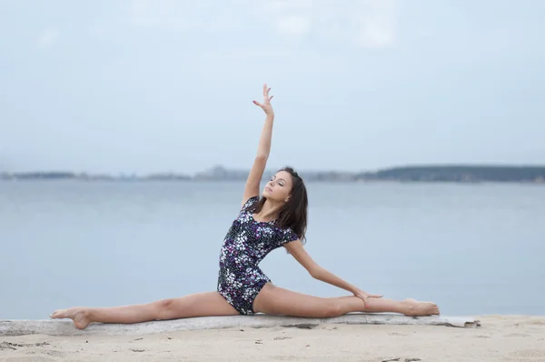 Молодая гимнастка танцует на пляже — стоковое фото