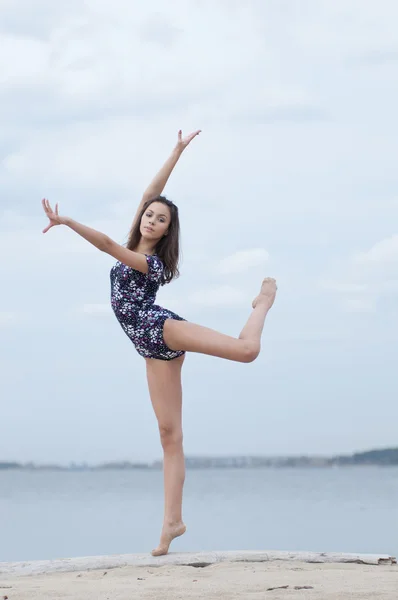 Unga gymnasten flicka dansa på stranden — Stockfoto