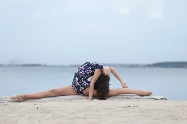 Unga gymnasten flicka dansa på stranden — Stockfoto