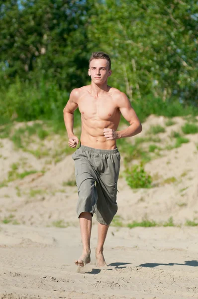 Young man running on beach — Stock Photo, Image