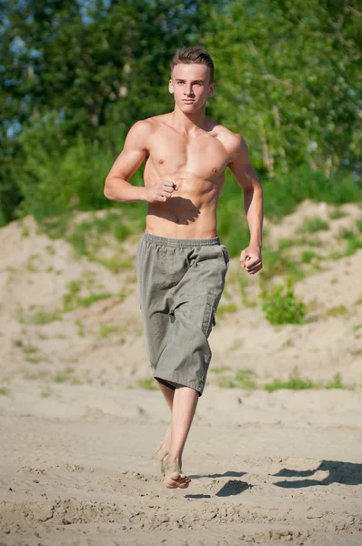 ビーチで実行されている若い男 — ストック写真