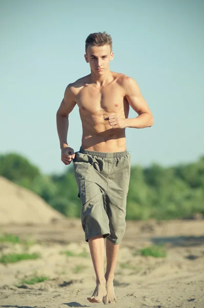 Jeune homme courant sur la plage — Photo