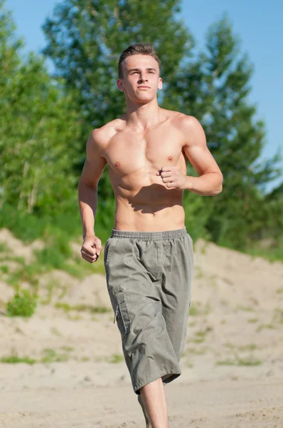 Junger Mann läuft am Strand — Stockfoto