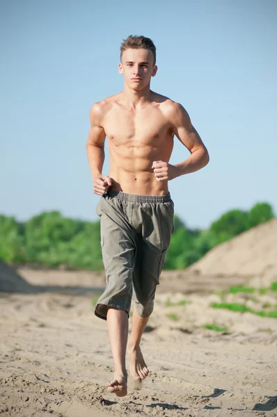 Junger Mann läuft am Strand — Stockfoto