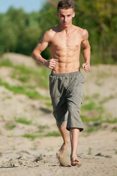 Young man running on beach — Stock Photo, Image