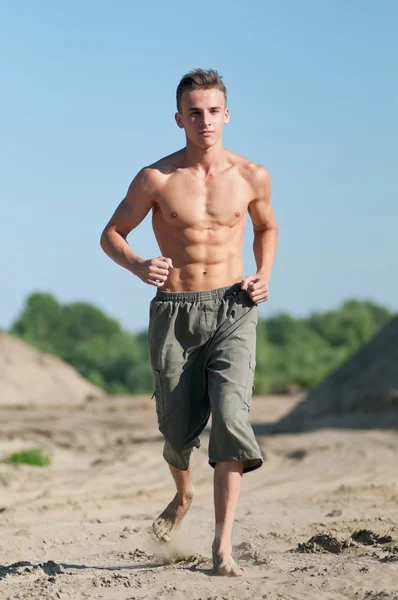 Junger Mann läuft am Strand — Stockfoto