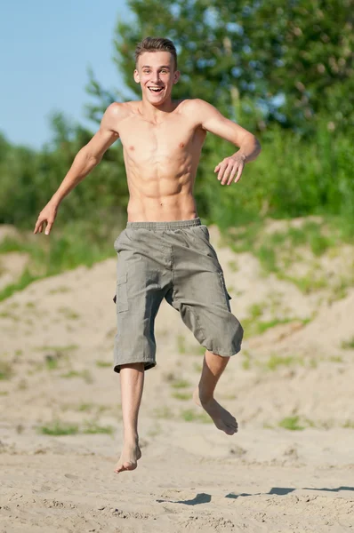 Young man running on beach — Stock Photo, Image