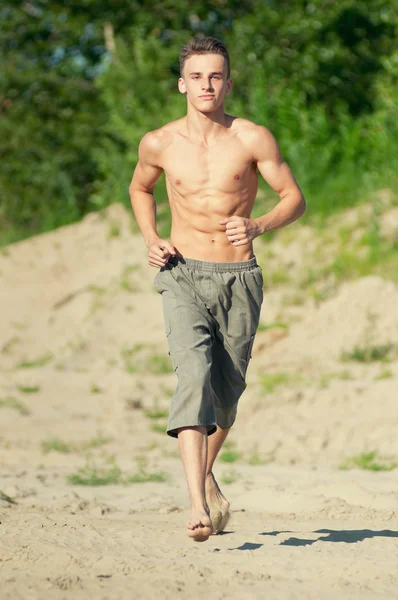 Young man running on beach — Stock Photo, Image