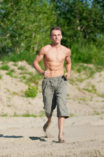Junger Mann läuft am Strand — Stockfoto