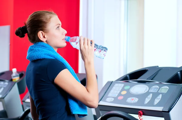 Mujer en el gimnasio bebiendo agua — Foto de Stock