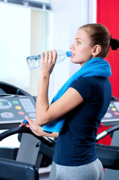 Женщина в спортзале пьет воду — стоковое фото