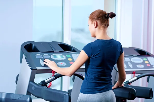 Giovane donna in palestra correre su una macchina — Foto Stock