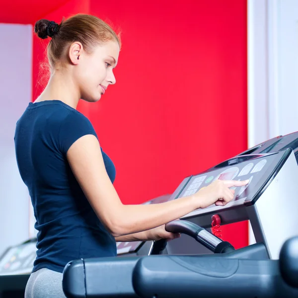 Giovane donna in palestra correre su una macchina — Foto Stock