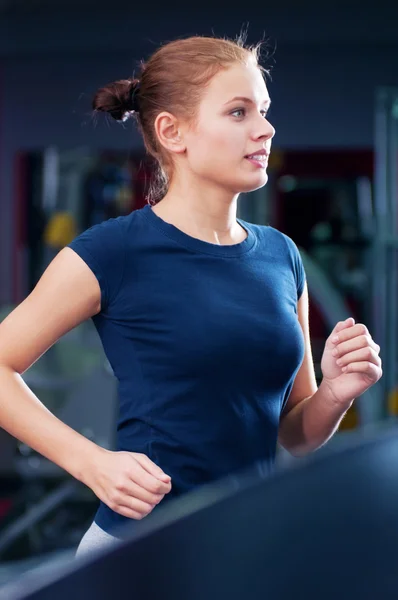 Mujer joven en el gimnasio se ejecuta en una máquina — Foto de Stock