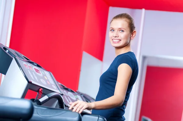 Junge Frau im Fitnessstudio läuft auf einem Gerät — Stockfoto