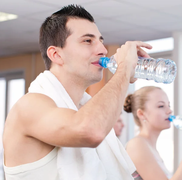 Man en vrouw drinkwater na sporten in de sportschool — Stockfoto