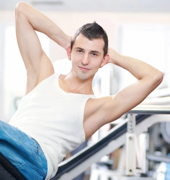 Молодой человек делает упражнения в спортзале — стоковое фото