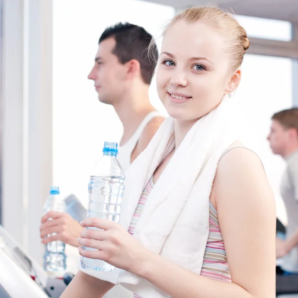 Mann und Frau trinken nach Sport in Turnhalle Wasser — Stockfoto