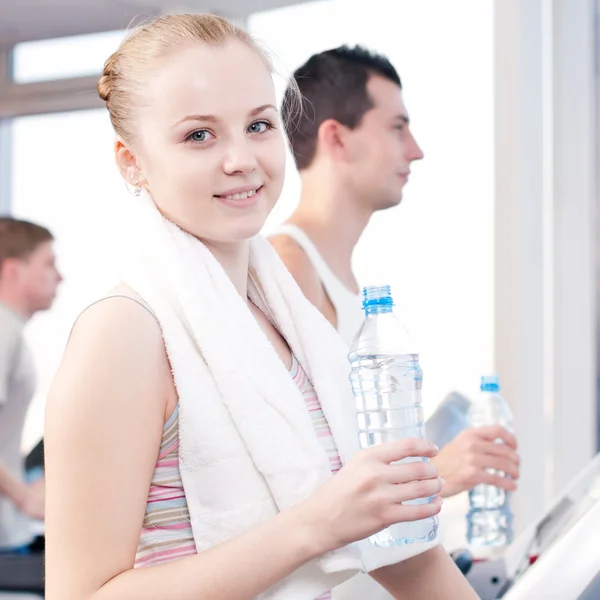 Mann und Frau trinken nach Sport in Turnhalle Wasser — Stockfoto