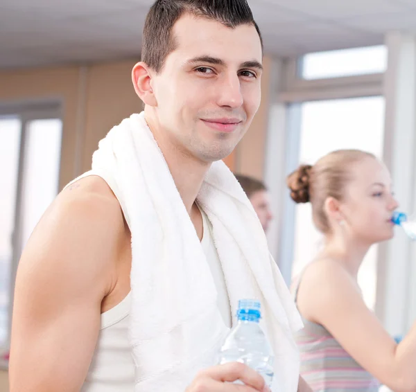 Man and woman drinking water after sports in gym — Stock Photo, Image