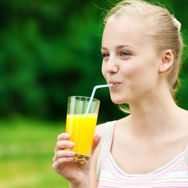 Giovane donna che beve succo d'arancia. All'aperto — Foto Stock