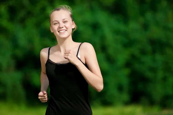 Young woman running in green park — Stock Photo, Image