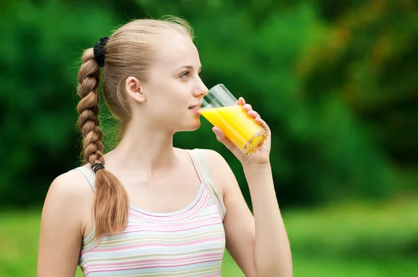 Ung kvinna dricker apelsinjuice. utomhus — Stockfoto