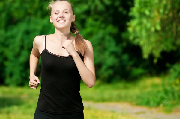 Young woman running in green park Stock Image