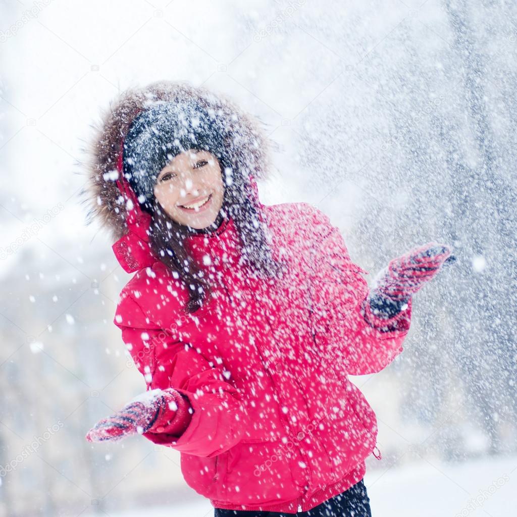 Happy young woman plays with a snow
