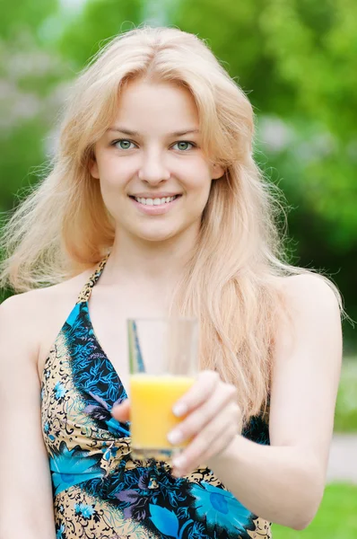 Mulher sorridente bebendo suco de laranja — Fotografia de Stock