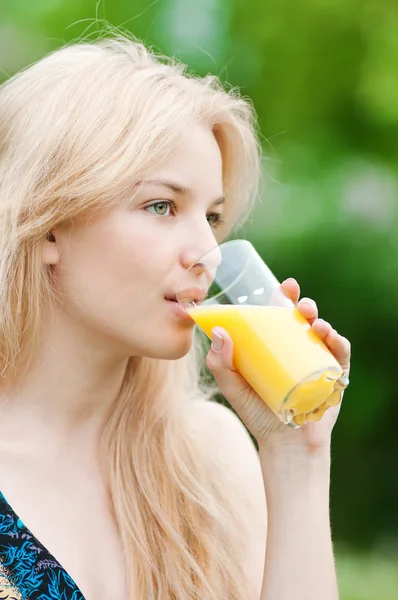 Mulher sorridente bebendo suco de laranja — Fotografia de Stock