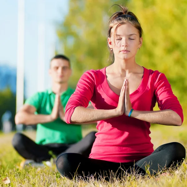 Homme et femme faisant du yoga dans le parc — Photo